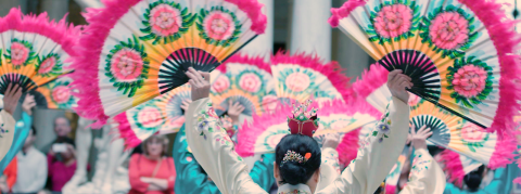 A group holds up hand fans during a performance.