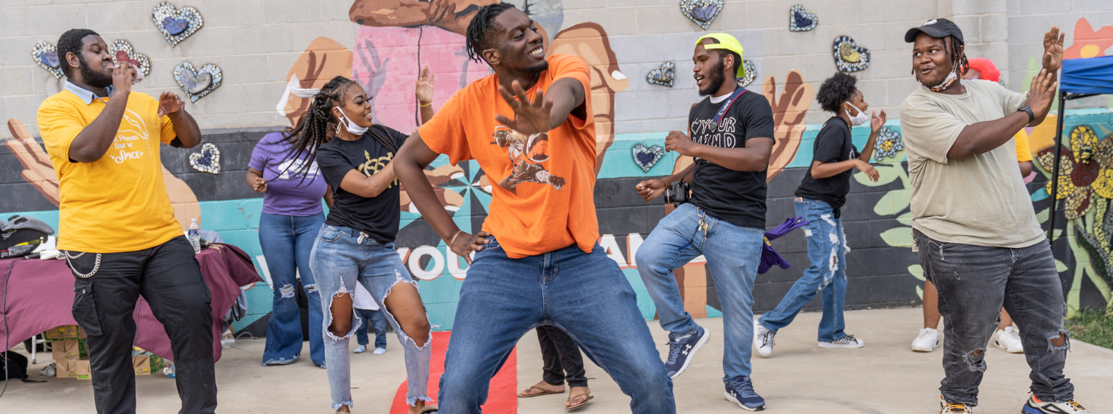 People dancing in front of a wall of graffiti.