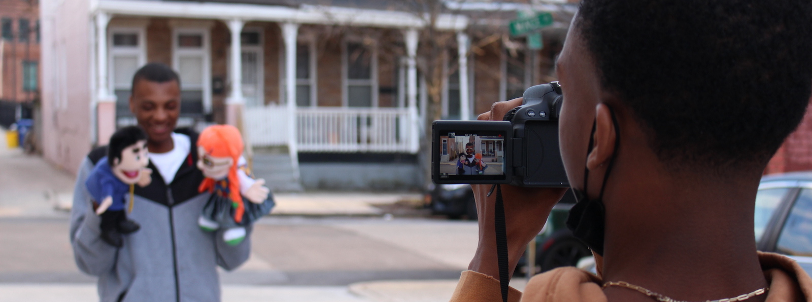 A person video recording another person performing with hand puppets.