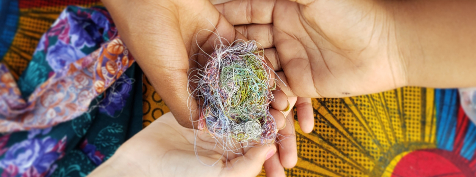 Three hands holding a ball of string.