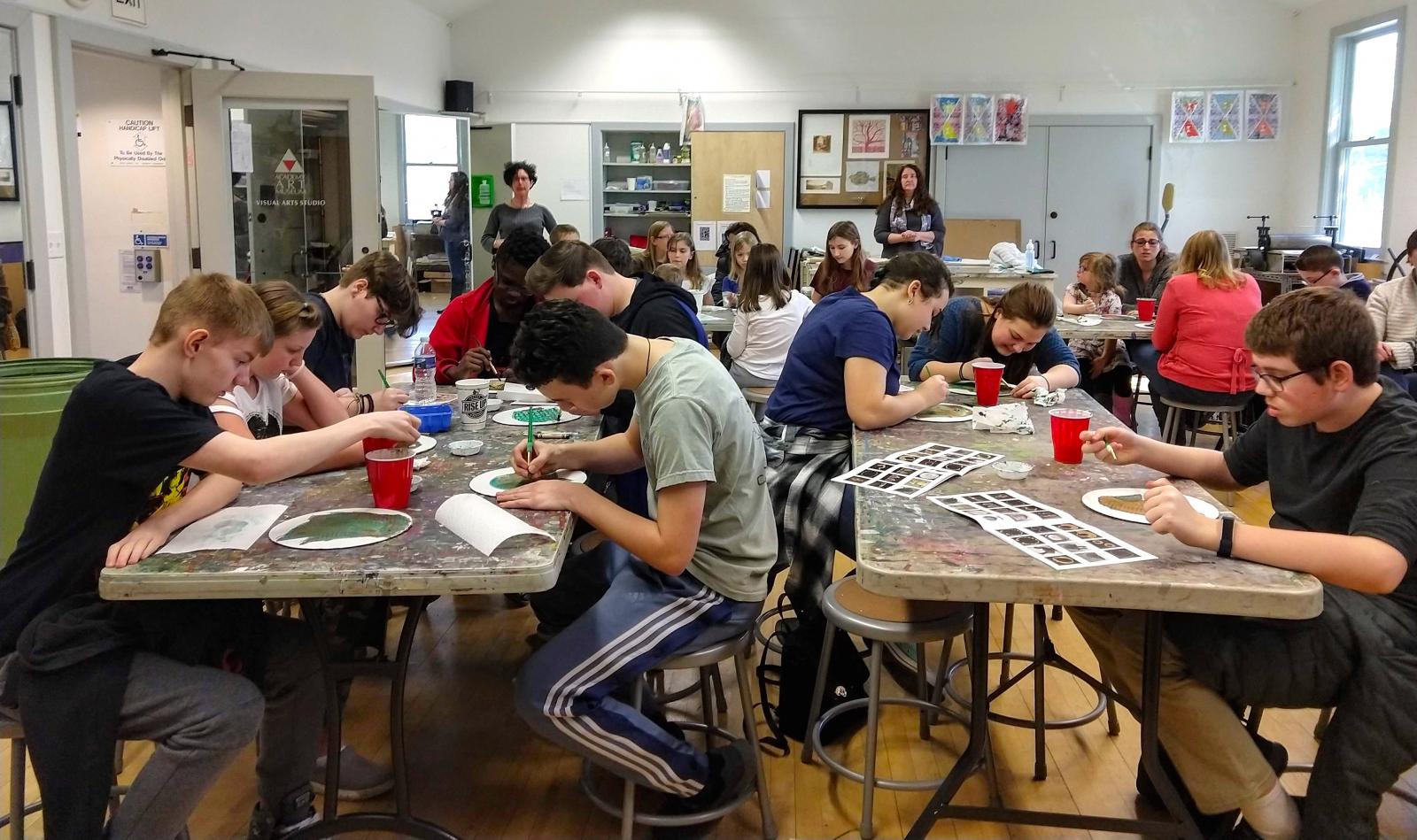 Full classroom of people sitting around tables